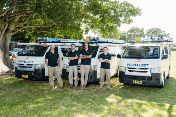 Powellect electricians standing with company service vehicles