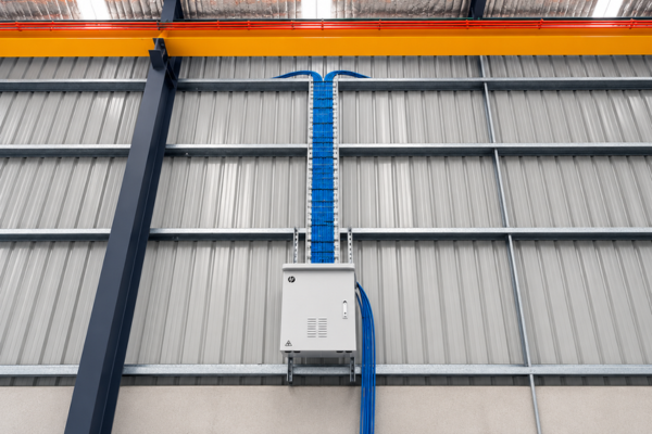 Data cabling installed by Powellect in vertical cable trays alongside an electrical enclosure inside an industrial building