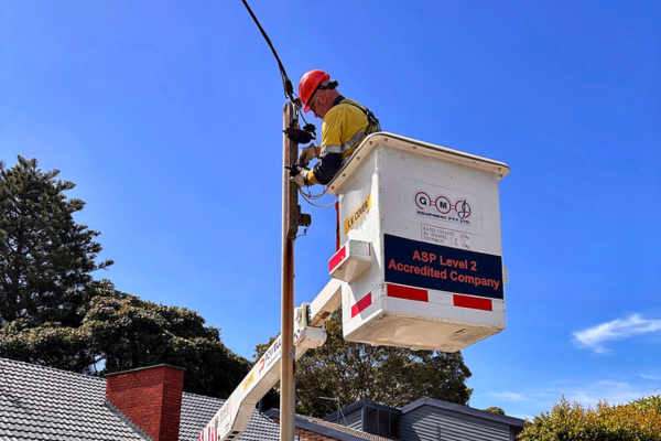 Powellect Level 2 electrician working on an overhead electrical supply connection from an elevated work platform beside a power pole