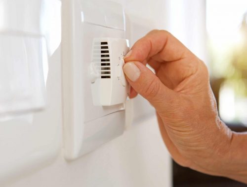 female hand adjusting temperature with dial on air conditioning home electrician Newcastle and residential electrician Newcastle