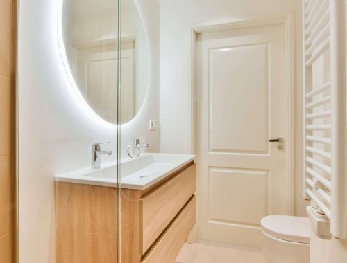 Luxurious bathroom with round large mirror with lighting home electrician Newcastle and residential electrician Newcastle